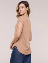 Remera blanca de punto acanalado con escote redondo adornado con tachas metálicas en el cuello y hombros, mangas cortas japonesas y ruedo curvo.