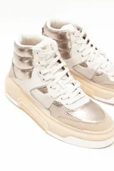 Championes de caña alta estilo botita, en tonos beige y dorado metalizado, con cordones y suela chunky de goma.
