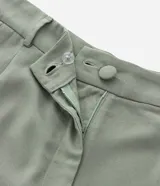 Bermuda de corte sastrero color verde oliva, confeccionada en mezcla de viscosa y lino. Presenta pliegues frontales, bolsillos laterales, trabillas para cinturón y cierre frontal con botón y cremallera.