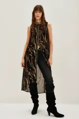 Camisa sin mangas, larga y abierta, con cuello alto y cierre frontal. Presenta un estampado abstracto en tonos marrón oscuro y dorado metalizado.