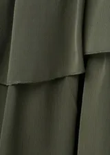 Vestido corto verde militar de diseño recto, con escote recto, tirantes finos y volantes en capas. Cuenta con forro interior.