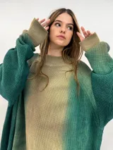 Buzo tejido de lana merino con diseño oversize, manga ranglan y cuello levemente elevado. Presenta un efecto de teñido degradado que combina tonos verdes y beige.