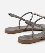 Sandalia plana color dorado, con diseño de tiras finas y aplicación de pedrería decorativa en la parte central. Cuenta con cierre de hebilla lateral ajustable.