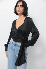 Camisa negra de seda con escote en V cruzado, mangas largas abullonadas y lazos para anudar en el frente.