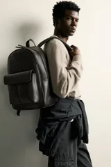 Mochila marrón oscuro con acabado abatanado, compartimento principal con cierre, bolsillo frontal con solapa y asa de mano.