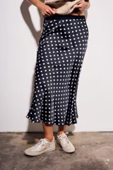 Falda midi de poliéster color negro con estampado de lunares blancos.