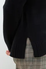 Sweater de punto en color celeste, con cuello redondo, mangas largas y puños acanalados. Presenta un diseño de corte holgado con costuras verticales decorativas en el frente.