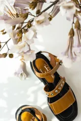 Sandalias de cuero color suela con acabado charolado, diseño de tiras con tachas metálicas y hebilla ajustable. Poseen una suela de goma negra tipo track con plataforma.
