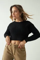 Sweater negro de punto con diseño trenzado, corte cropped, cuello redondo y mangas largas.