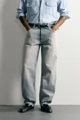 Pantalón denim de corte recto desde la cadera hasta el tobillo, de tiro medio y color celeste claro con efecto lavado. Cuenta con diseño clásico de cinco bolsillos y cierre frontal con cremallera y botón metálico.