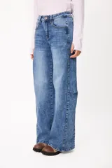 Jean de corte wide leg en color azul denim, con tiro medio y diseño de cinco bolsillos. Presenta costuras laterales marcadas y un acabado lavado.