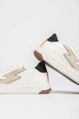 Championes Urban Haus modelo Lyon, de cuero blanco con detalles en color caramelo y beige. Presentan una suela gruesa blanca y logo de la marca en el lateral.