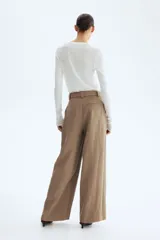 Pantalón de tiro alto con corte holgado y piernas amplias, color marrón, con pliegues delanteros y cinturón del mismo tejido con hebilla circular.