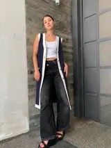 Vestido tipo chaleco azul marino con ribetes blancos, cuello en V, botones dorados y bolsillos frontales.