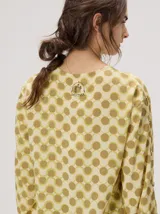 Camisa voluminosa de algodón con mangas amplias y abullonadas que se ajustan en los puños. Tiene calce suelto, hombro caído, cuello redondo y cierre frontal con botones. Presenta estampado geométrico en tonos mostaza y beige.