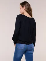 Blusa de modal y elastano color blanco, de silueta holgada, escote redondo amplio con elástico interno fruncido y mangas largas fluidas con puños ajustados.