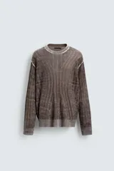Jersey de punto con diseño jacquard abstracto, cuello redondo y manga larga. Presenta un acabado texturizado con detalles de líneas verticales y terminaciones en rib en cuello, puños y ruedo.