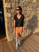 Remera negra de lentejuelas con cuello en V y tira vertical de cuero en el centro. Corte holgado.