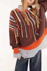 Sweater oversize de corte boxy, color crema con rayas verticales en tonos marrones y detalles de flecos colgantes. Presenta cuello redondo y puños y ruedo en tejido acanalado de color marrón oscuro.