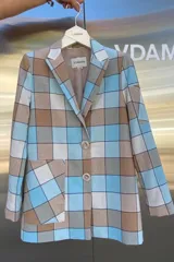 Blazer de corte recto con estampado a cuadros en tonos celeste, beige y blanco. Confeccionado en lino italiano de textura suave, cuenta con solapas clásicas, cierre con dos botones al frente y bolsillos amplios tipo ojal.