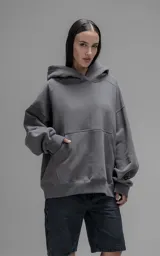 Hoodie oversize de corte crop, color gris oscuro, confeccionado en frisa de algodón. Presenta capucha forrada, bolsillo tipo canguro frontal y puños elásticos.