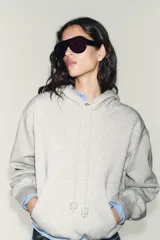 Sudadera de corte holgado con capucha ajustable mediante cordones con detalle de perlas en los extremos. Presenta mangas largas con puños elásticos y bajo con acabado tipo globo.