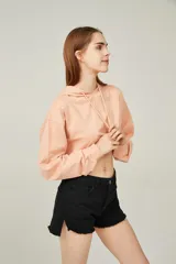 Buzo color durazno, corto, con capucha y mangas largas.