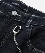 Pantalón de jean estilo baggy balloon, de corte holgado con volumen en las piernas y cintura fija con trabillas. Presenta costuras a contratono y detalle de cadena metálica lateral.
