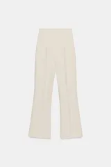 Pantalón de vestir color crudo, de tiro alto y pierna acampanada.