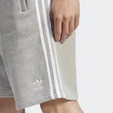Short Adidas Adicolor con tejido French terry, color gris con tres rayas blancas a los lados y logo bordado.