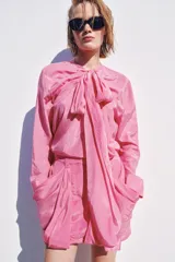 Falda mini de tiro medio color rosado, con trabillas en la cintura y bolsillos laterales con pliegues drapeados.