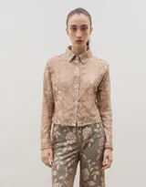 Camisa de encaje con diseño floral, de corte recto y manga larga, con cierre frontal de botones clásicos y cuello camisero.