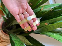 Pulsera rígida dorada con piedra circular blanca y pulsera rígida dorada con piedra circular roja.