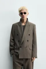 Blazer Zara de corte relajado confeccionada en mezcla de viscosa y lino. Presenta cuello con solapas de pico, cierre frontal de botonadura cruzada, bolsillos de solapa en la cadera y aberturas en la espalda.