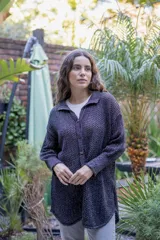 Camisa tejida en punto calado color marrón con hilo de algodón y lurex. Silueta oversize, mangas 3/4 ligeramente abullonadas, cuello camisero clásico y botonadura frontal con botones metálicos dorados.