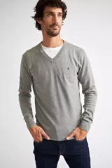 Sweater de tejido de punto en color gris melange, con escote en V, manga larga y logo bordado en el pecho. Presenta puños y ruedo acanalados.