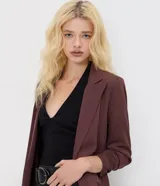 Blazer sastrero alargado color bordó de Blue Steel, confeccionado en poliéster con elastano y forro de poliéster. Presenta solapas clásicas, mangas largas fruncidas y diseño estructurado.