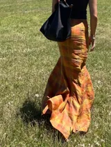 Falda larga de lino con estampado escocés en tonos otoñales (naranja, amarillo, marrón y rojizo). Diseño con gajos que le otorgan mucho movimiento, ajustada en la cadera y con vuelo en el ruedo (corte sirena o trompeta).