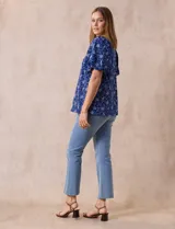 Blusa azul con estampado floral blanco, cuello cuadrado, mangas cortas abullonadas y frunce en los hombros.