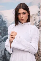 Camisa blanca de broderie con cuello alto, cuerpo y puños con frunces elásticos, y mangas largas abullonadas.