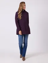 Campera capitoneada de largo midi en color bordó, con diseño de rombos en el cuerpo y mangas, y costuras diagonales en los laterales. Cuenta con cierre frontal, capucha desmontable con interior suave y panel entallado en la cintura.