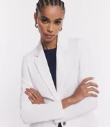 Blazer alargado color gris oscuro, con cuello solapa, bolsillos incorporados y cierre frontal con dos botones.