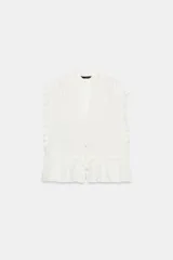 Top blanco sin mangas con escote en V, detalles de bordados frontales, volantes en los hombros y cierre frontal con botones.