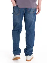Jeans de denim azul con calce slim, diseño clásico de cinco bolsillos, cierre de cremallera y botón, y costuras en contraste.