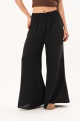 Pantalón palazzo negro de corte ancho, con cintura elástica fruncida y diseño fluido.