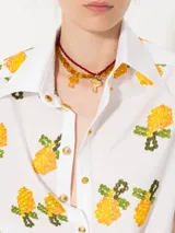 Camisa blanca de poplin con bordado de limones, jareta en la cintura con lazo ajustable, broches dorados, vivos blancos y puños en poplin rayado con ajuste mediante ojal y botón forrado.