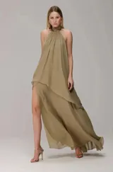 Vestido largo de frente única con diseño fluido y capas superpuestas. Presenta un cuello alto con detalle de cadena metálica integrada y una abertura lateral pronunciada en la falda.