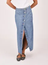 Falda larga de denim color gris oscuro, con diseño cruzado frontal (wrap) que se ajusta con botones plateados, creando una abertura pronunciada.