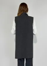 Chaleco largo color beige, con cuello solapa, un botón frontal y dos bolsillos de parche. Presenta costuras decorativas en contraste.