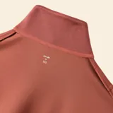 Chaqueta deportiva de color marrón rojizo, con cuello alto tipo camionero y cierre frontal parcial. Presenta mangas largas con puños elásticos, un bolsillo frontal tipo canguro y ruedo con elástico.
